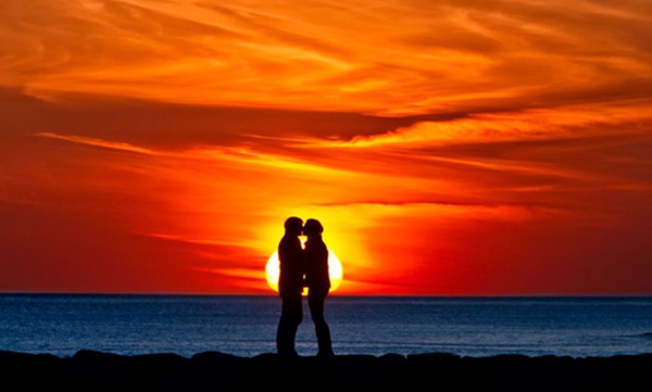 coppia che si bacia davanti al tramonto